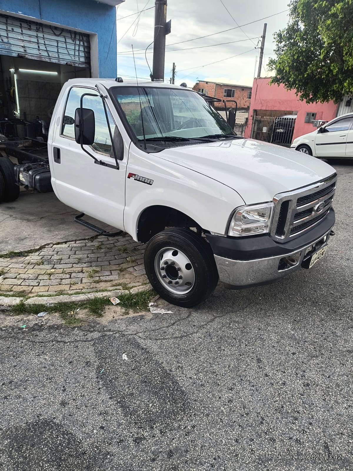 caminhão Ford F4000 branco chassi parado em frente a uma oficina