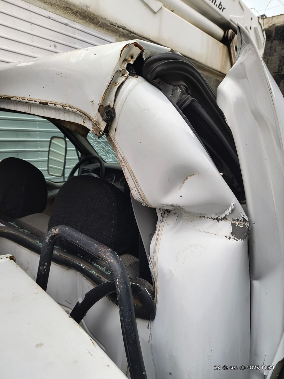 caminhão branco com a cabine amassada e danificada após colisão, com vidro estilhaçado